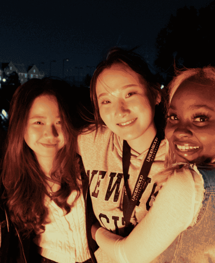 A student enjoying a social moment outdoors, smiling warmly with friends.