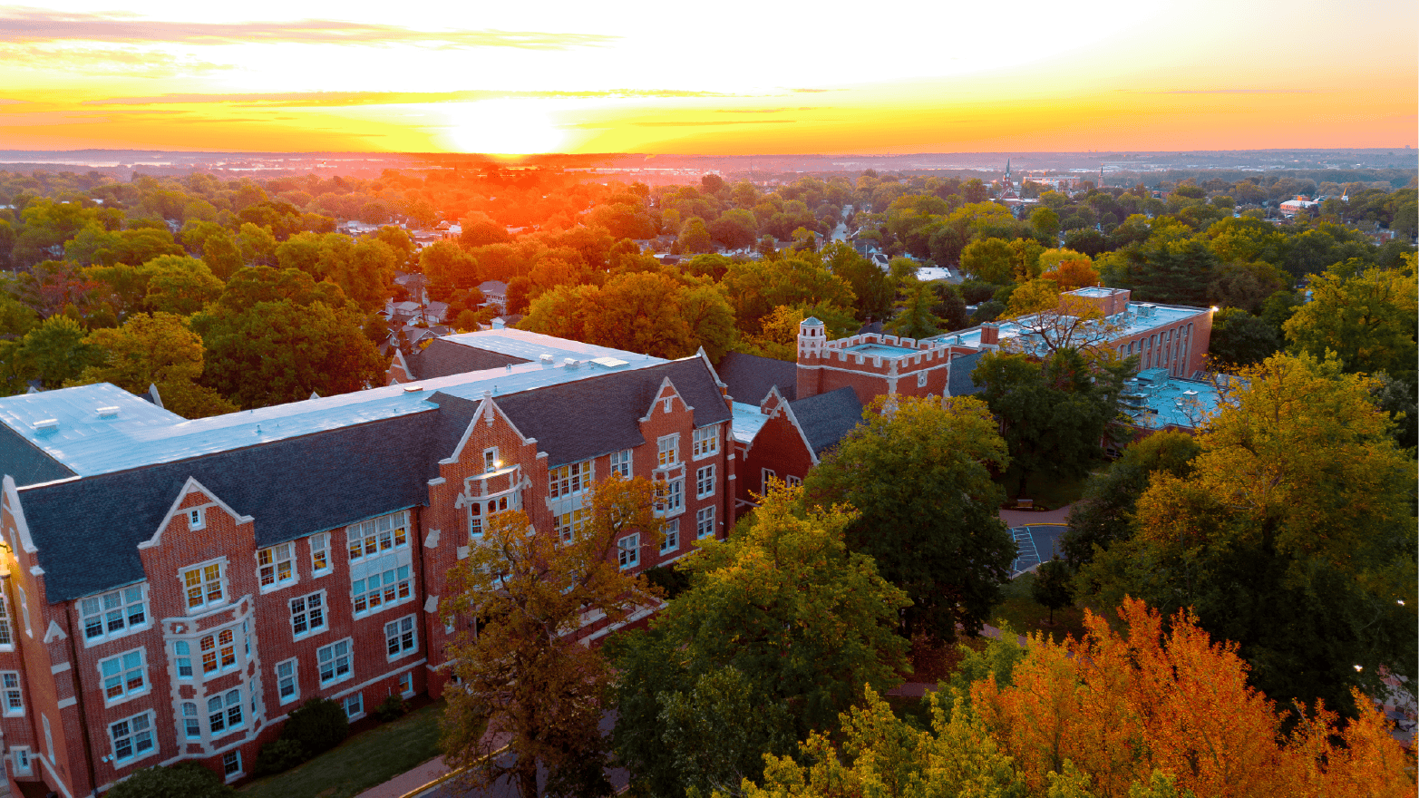 An aerial view of the Lindenwood University campus, showing buildings, fields, and greenery, with a video play button overlay.