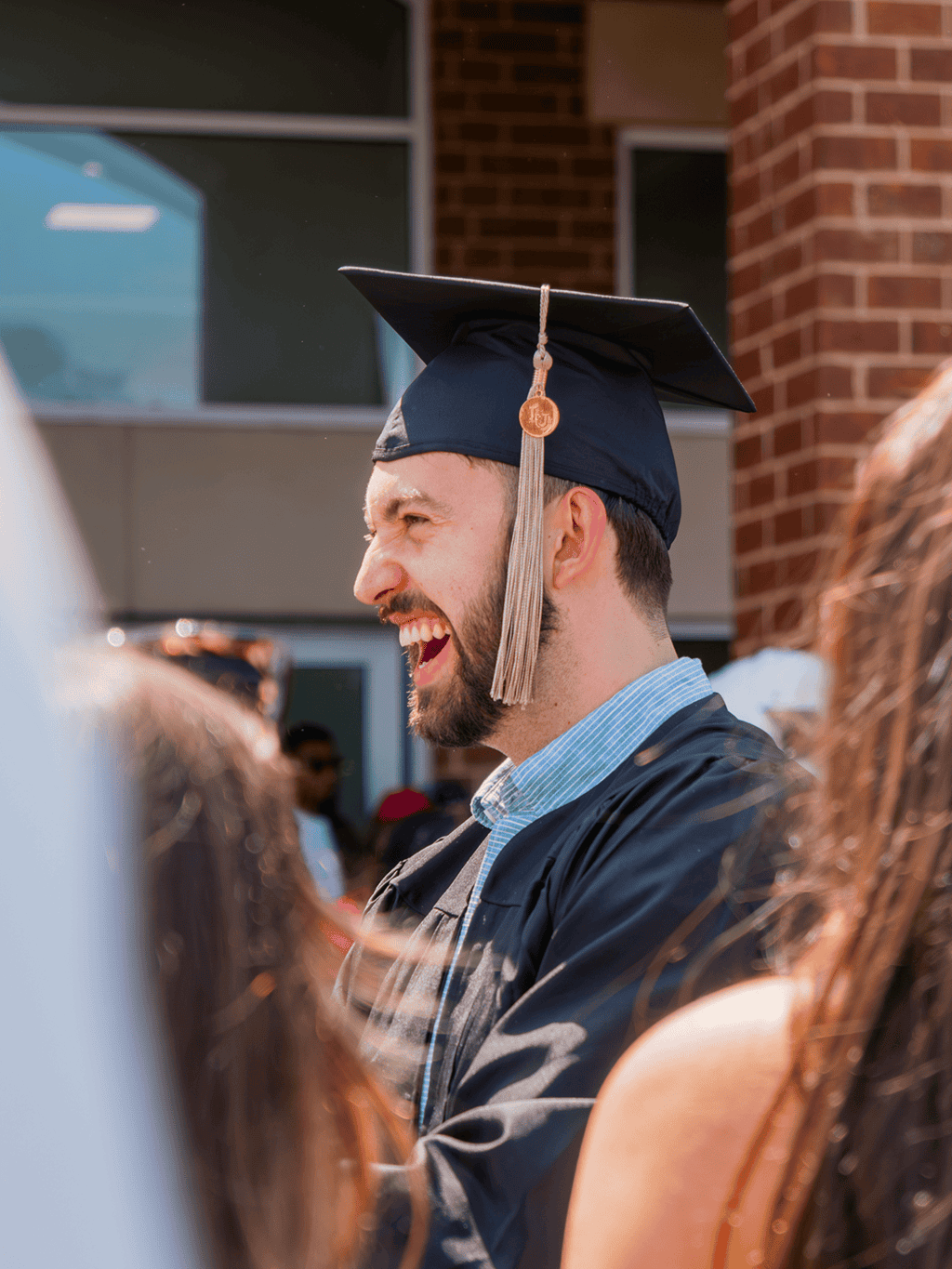 A graduate smiling in a cap and gown during a graduation ceremony.